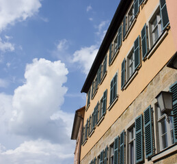 Facade of a European house with green shutters against a blue sky and clouds on a bright Sunny day.Urban architecture of the old city.