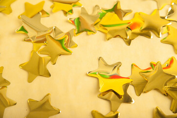 Christmas background in gold color. Yellow confetti stars out of focus.