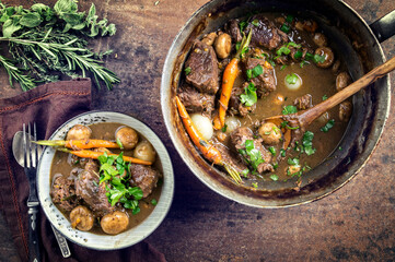 Traditional French boeuf bourguignon with vegetable farmhouse bread offered as top view in a design...