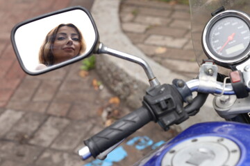 Fototapeta na wymiar Female pretty face in the mirror of the motorcycle