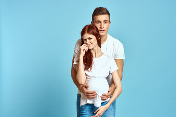 Pregnant woman in white t-shirt and man married couple waiting for baby blue background cropped view of emotions