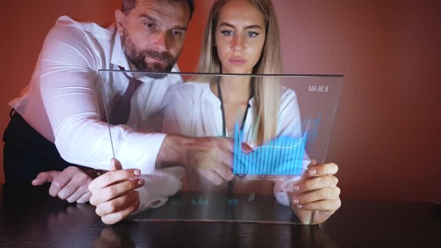Male With Female Coworker Looking and Scrolling Charts on Futuristic Transparent Tablet Device. Motion Graphics Animation, Future Business Concept