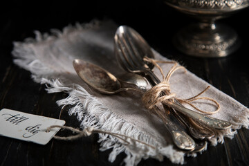 
Old spoons and forks tied with a scourge on a wooden table. The lettering on the badge is for you