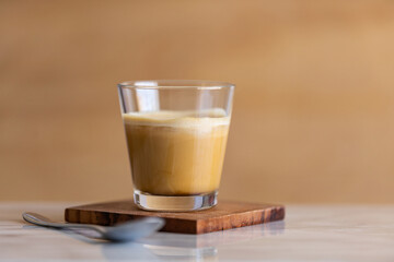 Ice coffee with milk in a glass on a marble counter. Copy space.