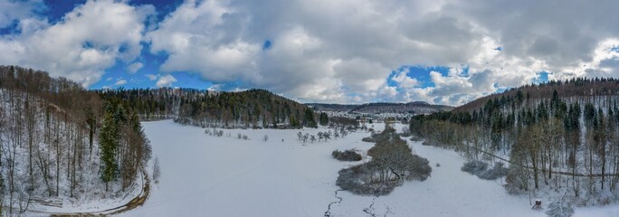 Idyllic winter pano in germany, swabian alb with snowy forest trees at the blue sky day.