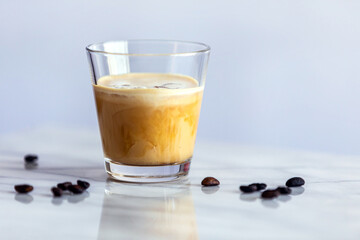 Ice coffee with cream on a marble counter with roasted coffee beans.