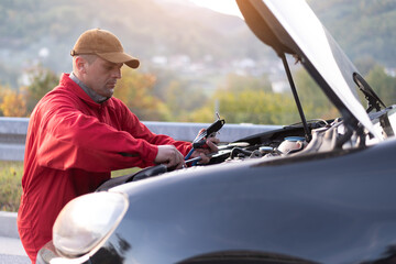 Emergency roadside assistance, road assistance worker in uniform trying to fix car breakdown or...
