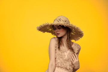 Woman in a straw hat in her hands on a yellow background emotions cropped view 