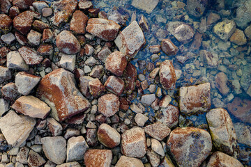Top view of the rocky seashore. Stones on the shore at low tide. Aerial view of shallow water. The natural background is great for design.