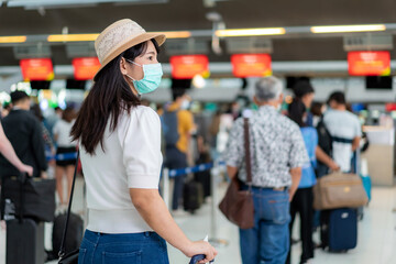 Asian woman traveler wearing mask holding passport at customer check in of airline service counter when traveling by airplane transportation for new normal travel concept..