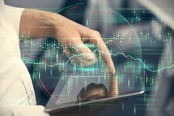 Double exposure of man's hands holding and using a digital device and forex graph drawing. Financial market concept.