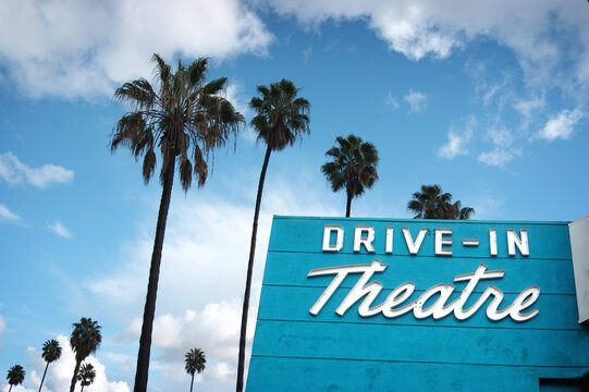 Aged and worn retro neon drive-in theater sign with palm trees