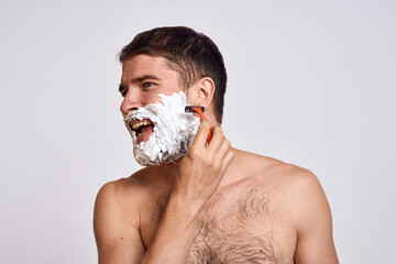 Handsome man with white shaving foam on his face and clean skin with razor grooming bare shoulders