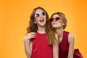 Happy woman and little girl in red dress are having fun on a yellow background fashion emotions sisters fun Copy Space.