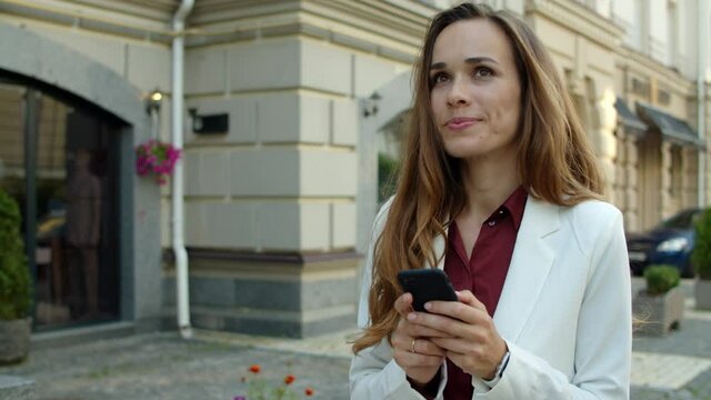 Happy business woman texting message online on smartphone outdoors