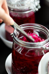 Reaching for bright pink sauerkraut pickles from inside jar