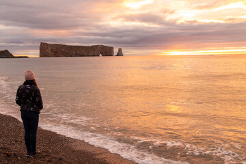 Peaceful view of a woman admiring the sunset on the beach of Percé, Canada