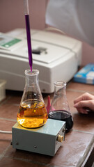 Researcher is making a test, dropping blood in an erlenmeyer flask, hands only visible