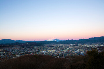 朝日に照らされる富士山と夜明けの街並み