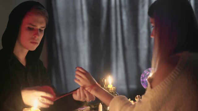 Side view of fortune teller man tied red rope on woman's hand