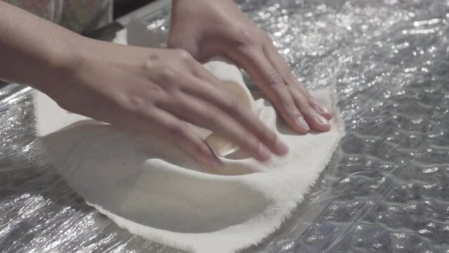 close up of brunette girl's hands preparing raw fabric for tie dye technique