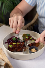 Man is eating beef loin in teriyaki sauce with knife and fork, close up