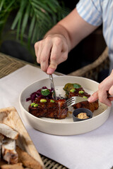 Man is eating beef loin in teriyaki sauce with knife and fork, close up