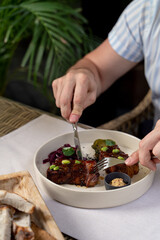 Man is eating beef loin in teriyaki sauce with knife and fork, close up
