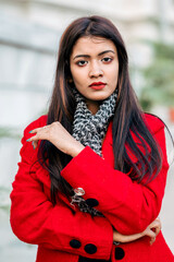 Outdoor close up portrait of young beautiful woman posing on street of Asian city, looking at camera, aside. Model wearing stylish winter coat, round sunglasses, black scarf. Female fashion concept.