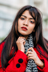 Outdoor close up portrait of young beautiful woman posing on street of Asian city, looking at camera, aside. Model wearing stylish winter coat, round sunglasses, black scarf. Female fashion concept.