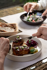 People elegantly eating gourmet meals in a restaurant, daylight photo, hands only visible