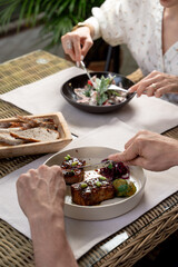 Date of an adult couple in a fancy restaurant, people neatly eating with knife and fork, close up, no faces, hands only visible