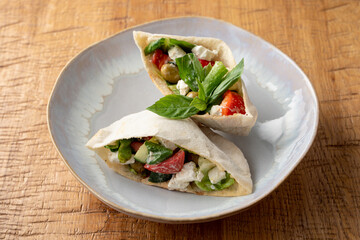 Greek pita with salad, feta and olives on a white plate, close up, high angle