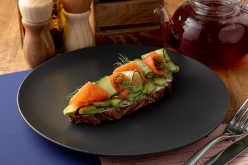 Whole grain rye bruschetta with cream cheese, vegetables and smoked salmon on a long slice of grilled crunchy toast