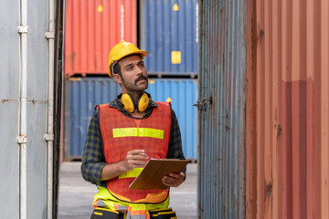 Portrait of confident inspector standing in front of containers in port. Dock worker with clipboard checking cargo freight shipping, Concept of transportation, logistics business.