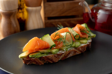 Close up of rye bruschetta with cream cheese, vegetables and smoked salmon on a long slice of...