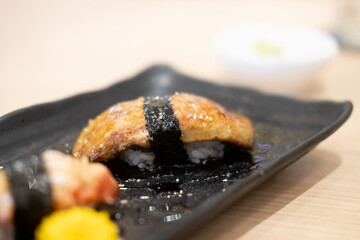 Foie gras sushi on black plate in Japanese restaurant.