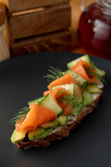 Close up of rye bruschetta with cream cheese, vegetables and smoked salmon on a long slice of grilled crunchy toast