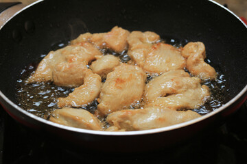 The oil is boiling in pan with Frying chicken by gas stove.