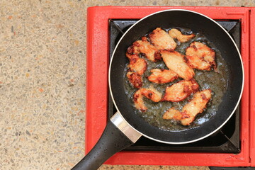 Top view Frying meat in a black pan on a gas stove.