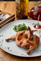 Whole roasted quail with golden crust, served with chili and tzatziki sauce in a mediterranean restaurant, top view, high angle