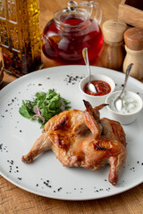 Whole roasted quail with golden crust, served with chili and tzatziki sauce in a mediterranean restaurant, top view, high angle