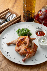 Whole roasted quail with golden crust, served with chili and tzatziki sauce in a mediterranean restaurant, top view, high angle