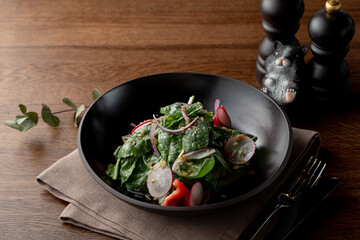 Summer salad with spinach and radish, dressed with crushed pistachio nuts