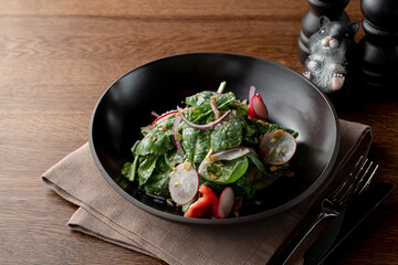 Summer salad with spinach and radish, dressed with crushed pistachio nuts