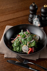 Top view of spinach and radish salad on a wooden table in a small restaurant, appetizing commercial photo
