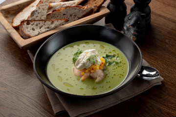 Gourmet pea soup with crab meat and shrimps on wooden table in a fancy restaurant