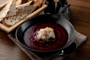 Cold russian beetroot soup with scallop in a russian fancy restaurant, top view on wooden table