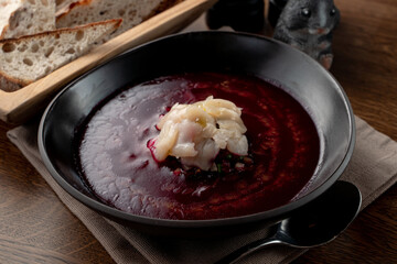 Close up of traditional russian cold soup svekolnik with scallop on wooden table with spoon aside