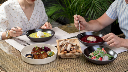 An adult couple having lunch on a summer terrace of a posh restaurant, set table with fine dining meals, no faces
